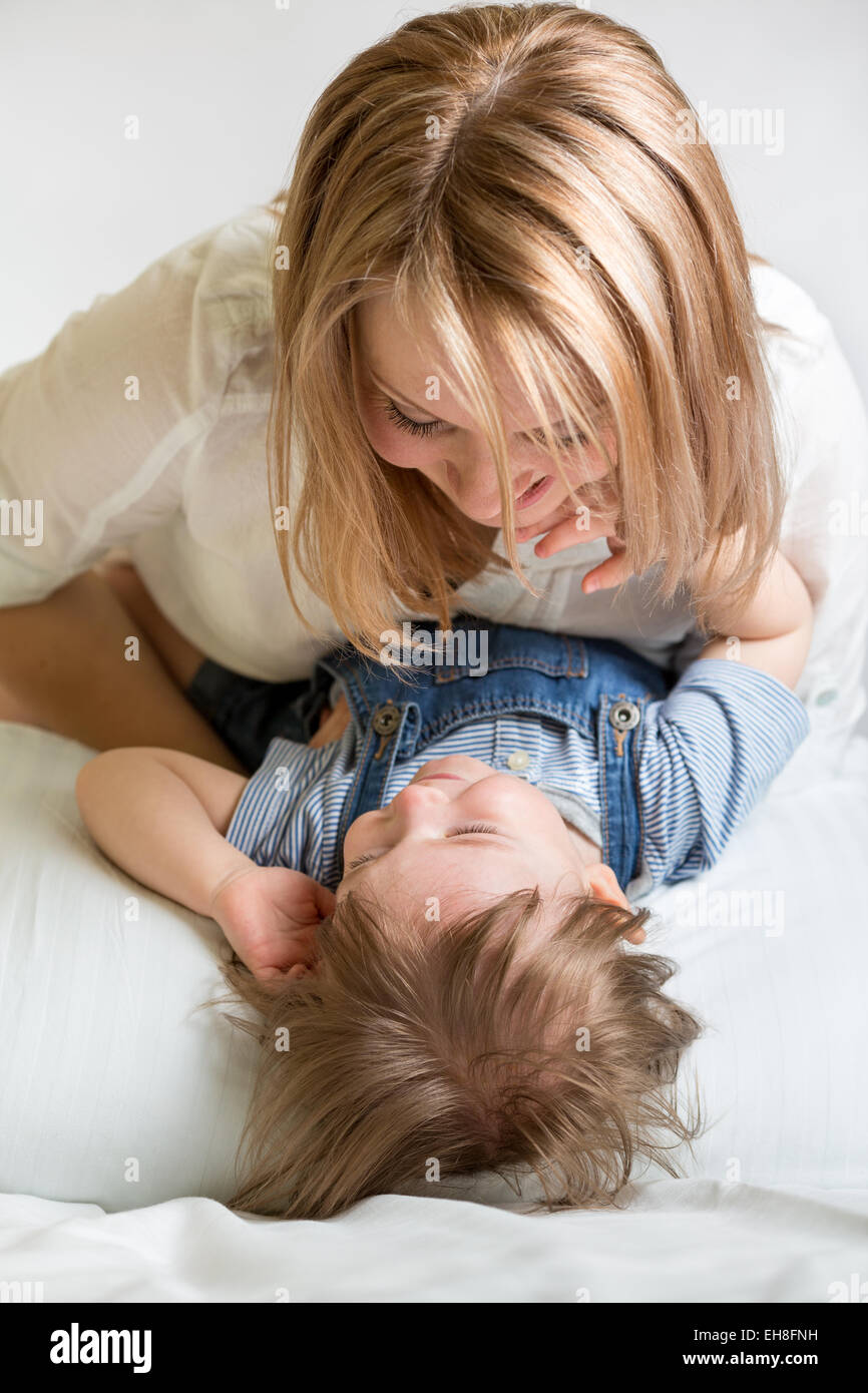 mother and her kid lying on the bed and smiling Stock Photo