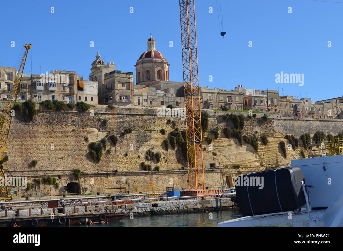 Continuing the trip around the Harbour of Malta we pass a number of boats that are tied up there. Above them looms Valletta. Stock Photo