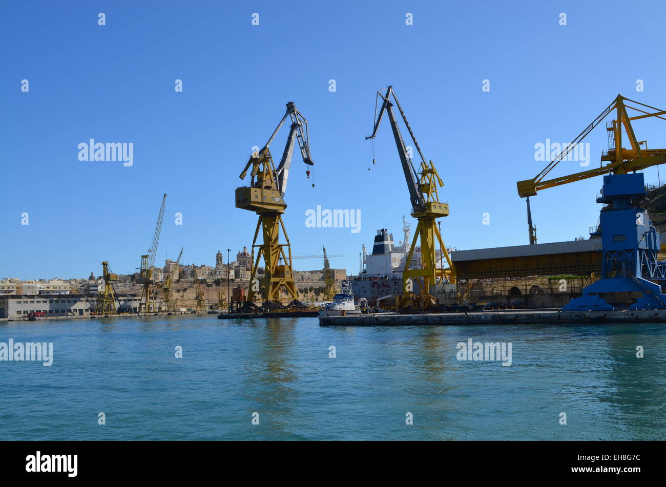 Continuing the trip around the Harbour of Malta we pass Two cranes busy unloading some goods for the harbour.. Stock Photo