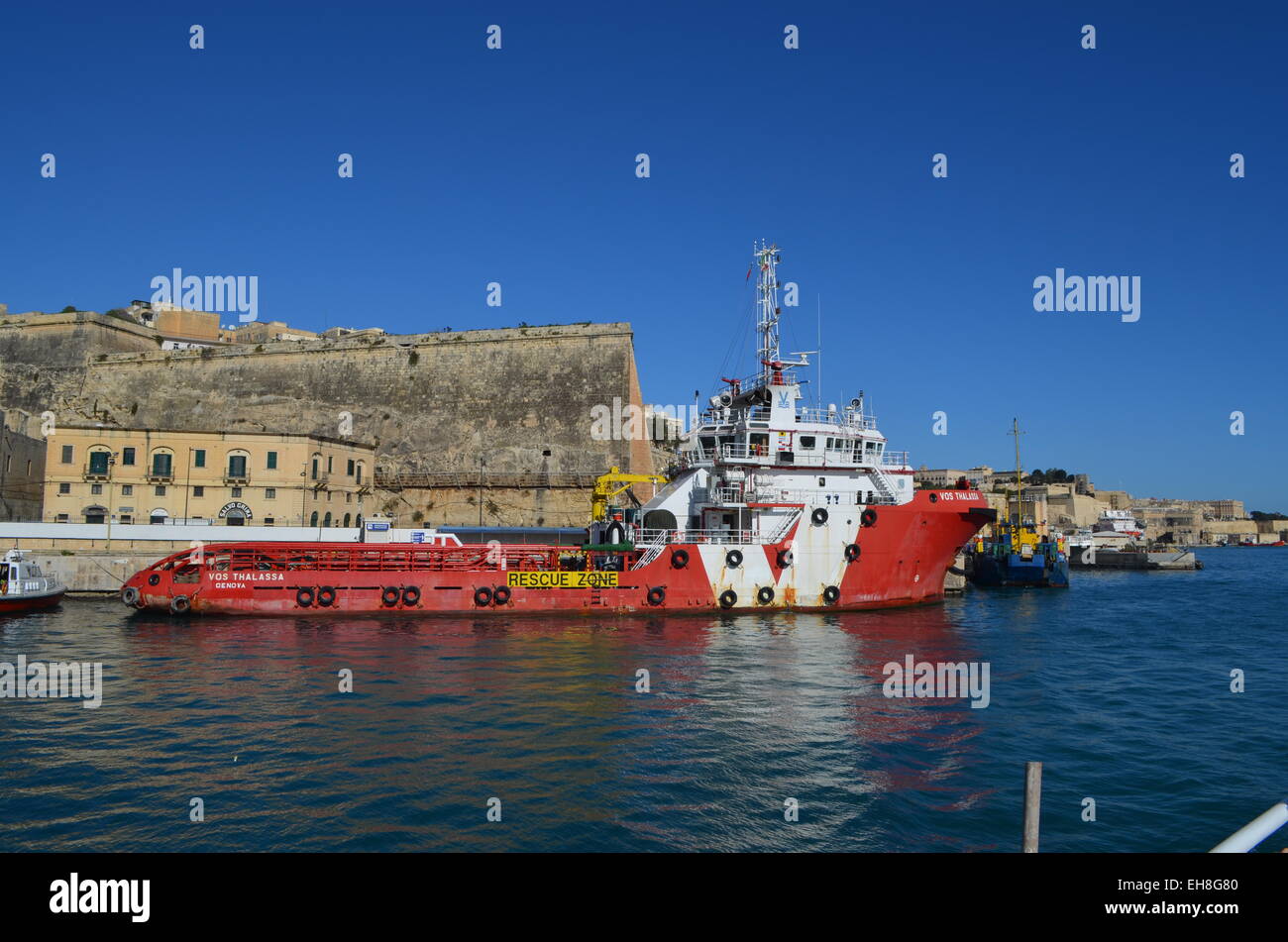 Cruising round the inner walls of the Grand Harbour we pass by another boat moored there under the packed city of Valletta. Stock Photo