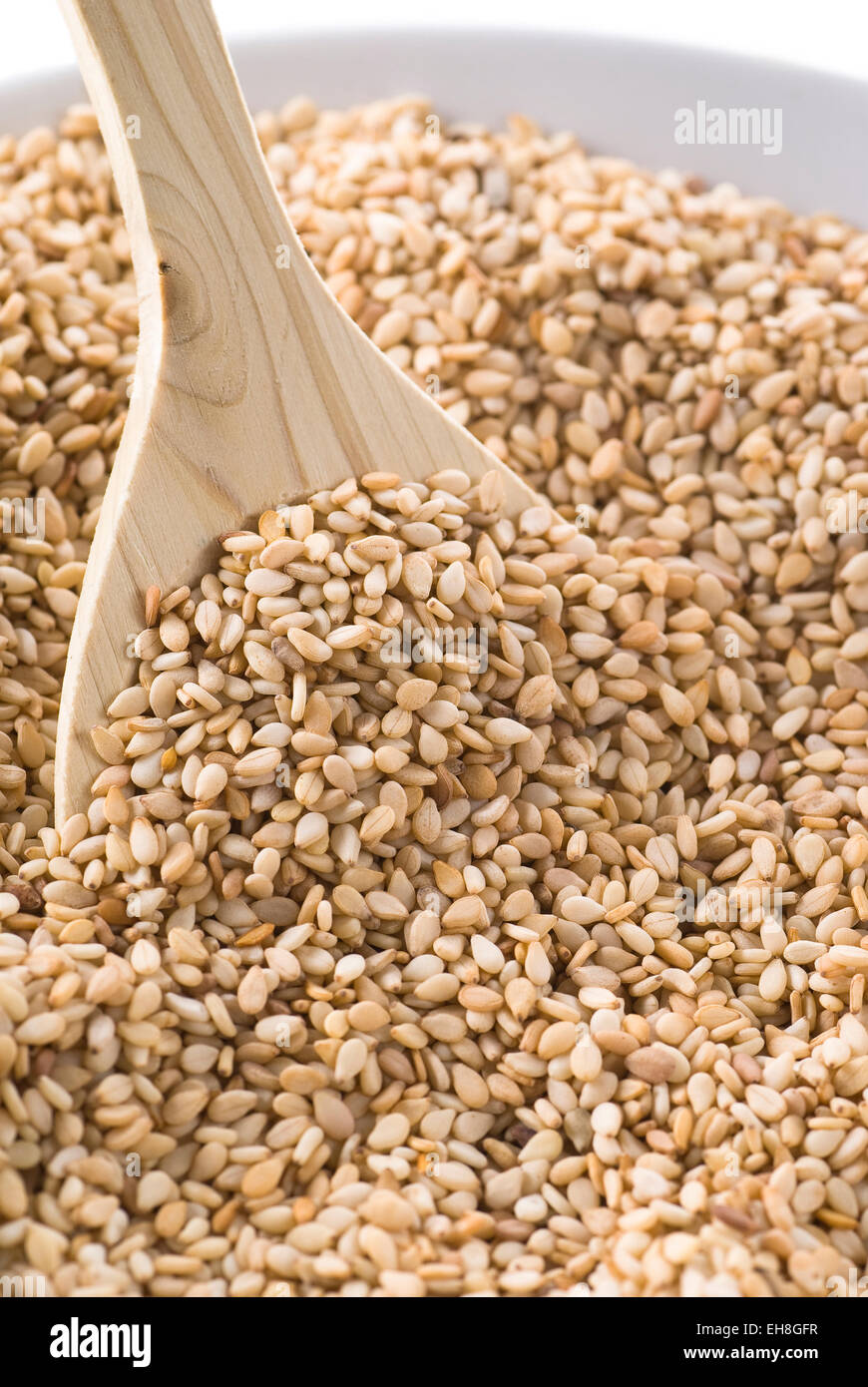A bowl with sesame seeds with a wooden spoon. Stock Photo