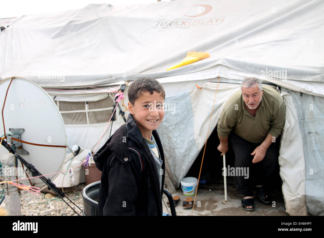 Kahramanmaras, Turkey. 3rd Mar, 2015. Mohammad (L) from Syria stands next to his tent with his father in the refugee camp in Kahramanmaras, Turkey, 3 March 2015. More than 3.8 million Syrians have escaped the civil war in Syria since the beginning of the war four years ago on Sunday 15th March. Mohammad, who would like to become a physician, is one of 1, 6 million refugees who have found refuge in Turkey. No other country has been harbouring more refugees. The situation of Syrian refugees, however, remains hopeless despite the Turkey's strong efforts. Photo: Can Merey/dpa/Alamy Live News Stock Photo