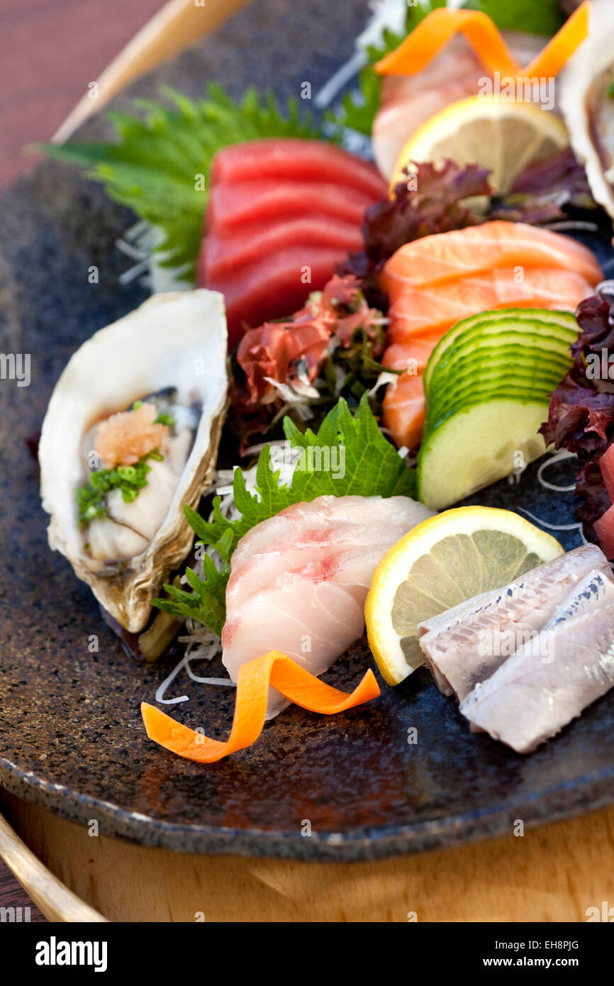 Raw fish, salad and oyster on a plate Stock Photo