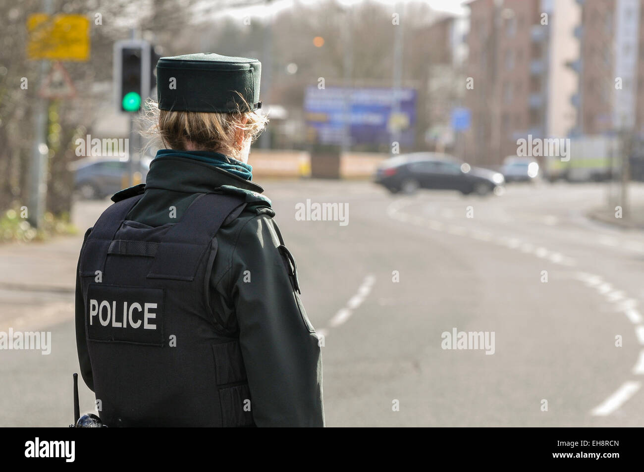 A police woman stands guard at a road in Belfast, while army ATOs defuse a bomb which was left in a residential area. Stock Photo