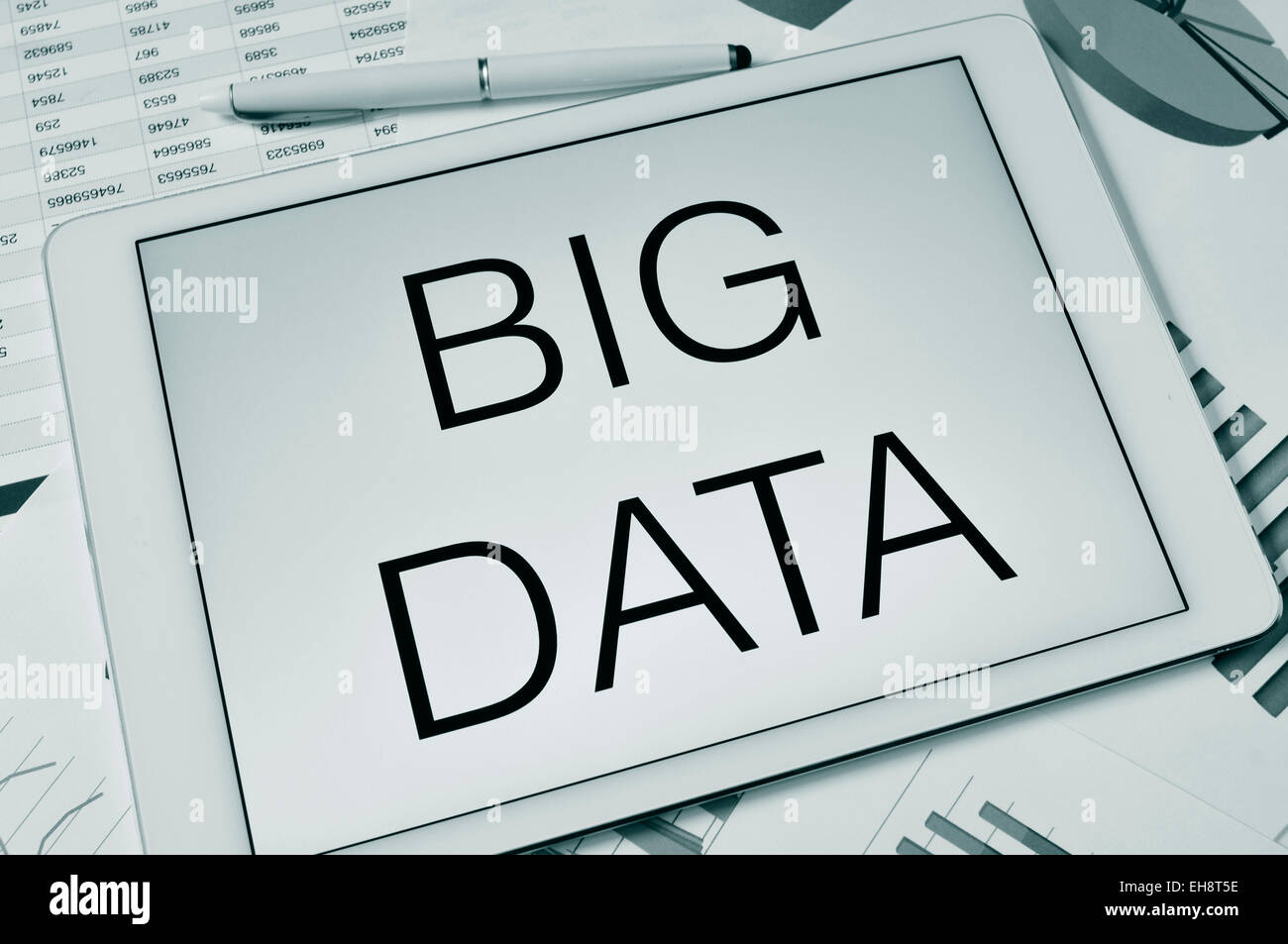 the text big data in the screen of a tablet on a table with charts and spreadsheet, in black and white Stock Photo