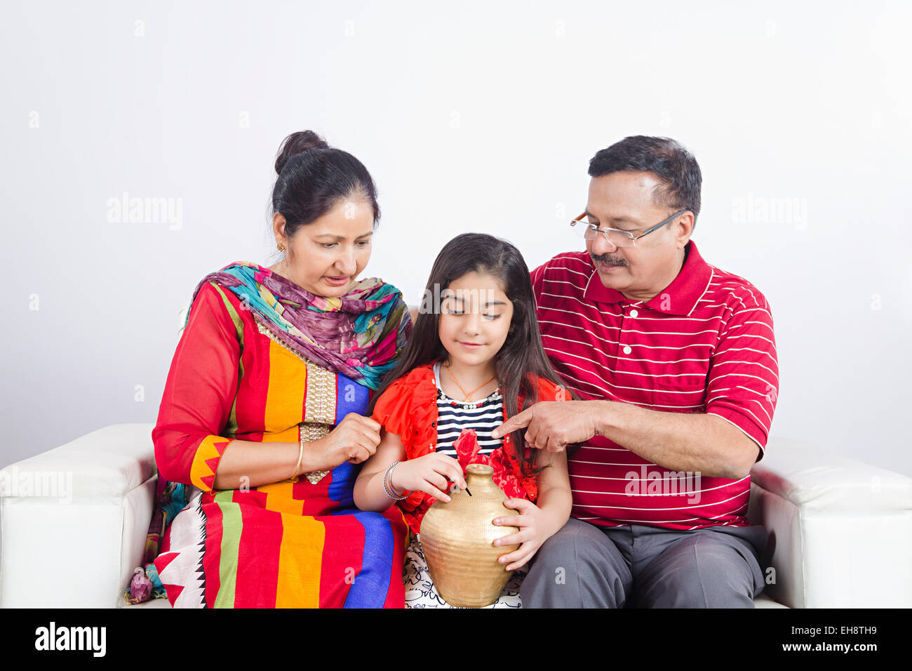 3 indian grand parents and kid Grand daughter sitting sofa Piggy Bank ...