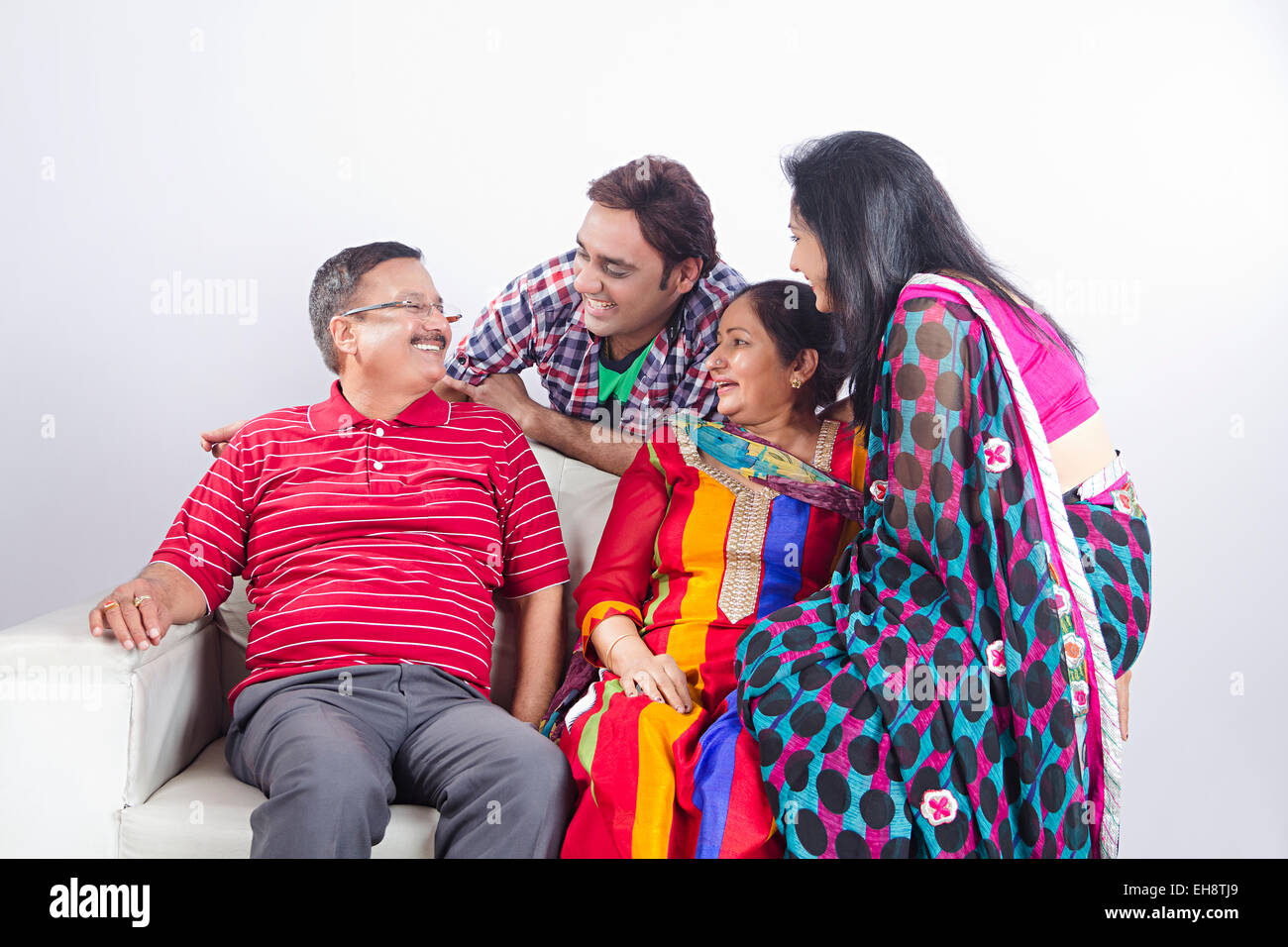 4 indian Adults Parents son and Daughter-In-Law sitting sofa Stock Photo
