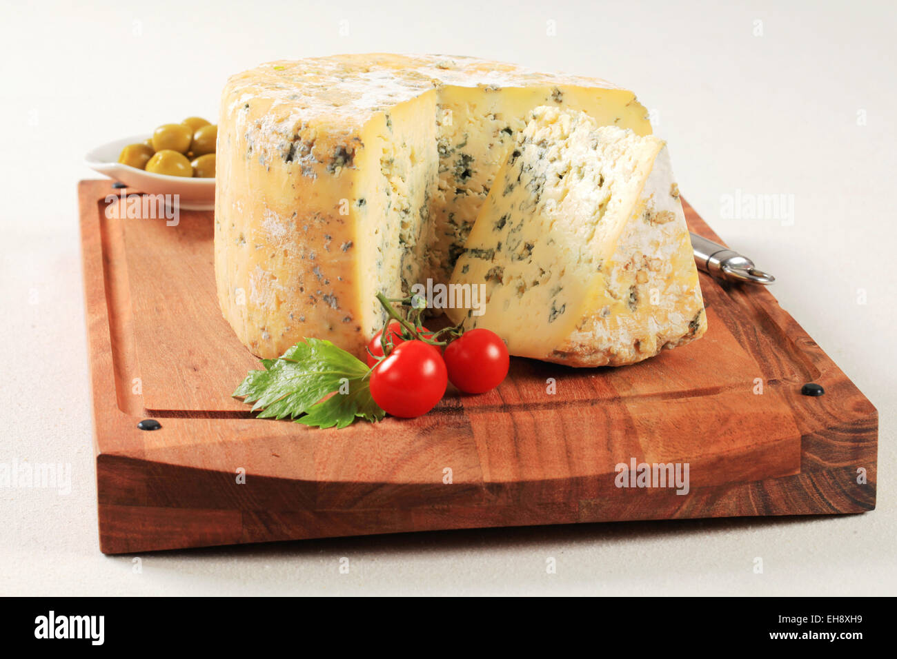 Wheel of blue cheese on cutting board Stock Photo