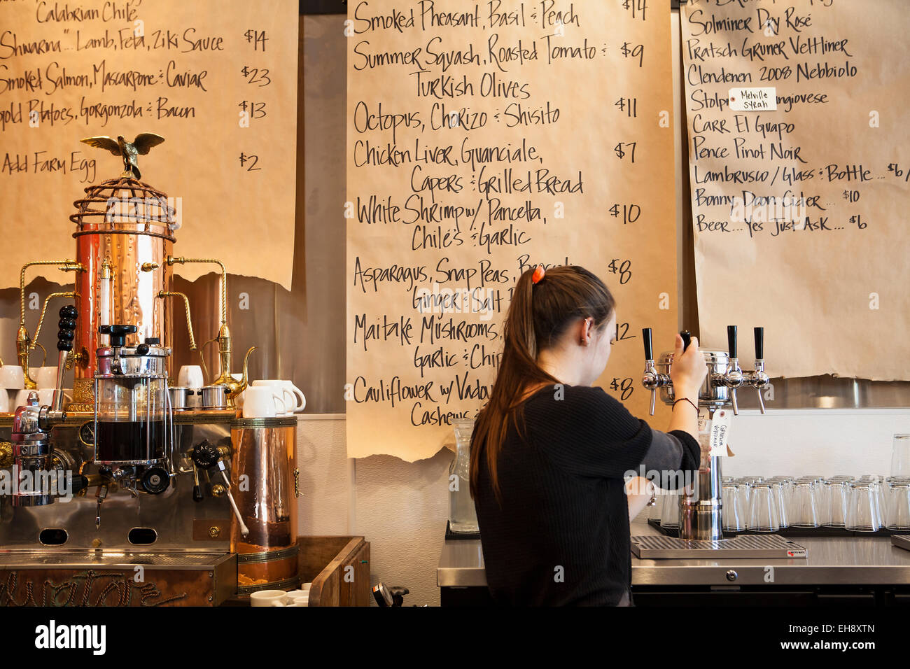 server pours a glass of viognier with menus on brown paper rolls, Industrial Eats, Buellton, California Stock Photo