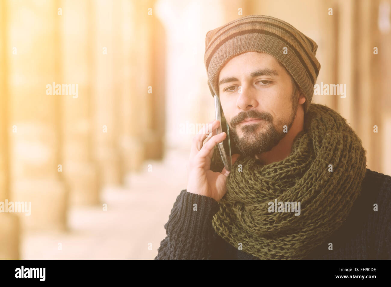 Lifestyle portrait of a young man using a smart phone outdoors warm tones filter applied Stock Photo