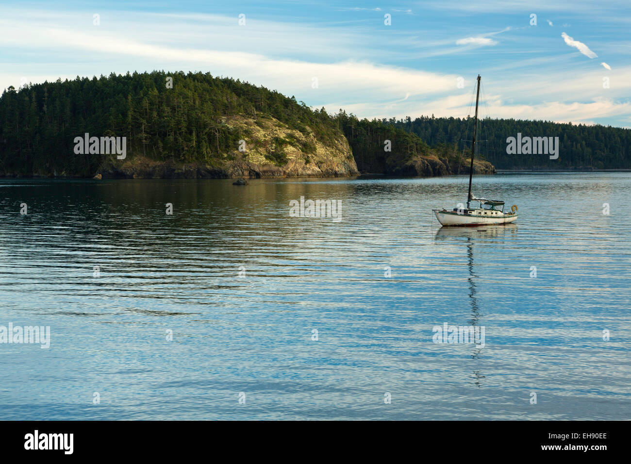 A sail boat is safe in harbor at Bowman Bay on Whidbey Island at sunset. Stock Photo