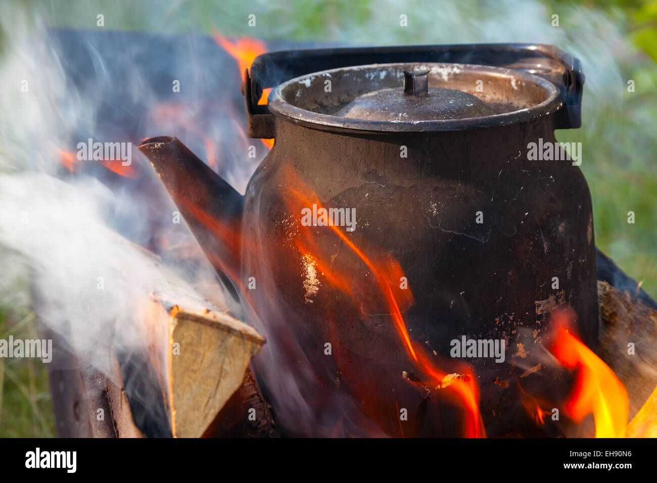 Bonfire with metal old black boiling teapot on it Stock Photo