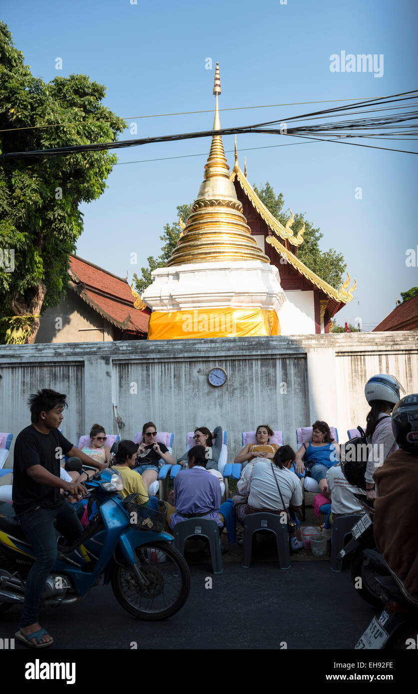 Tourist enjoying a Thai foot massage in the streets of the old city of Chiang Mai. Stock Photo