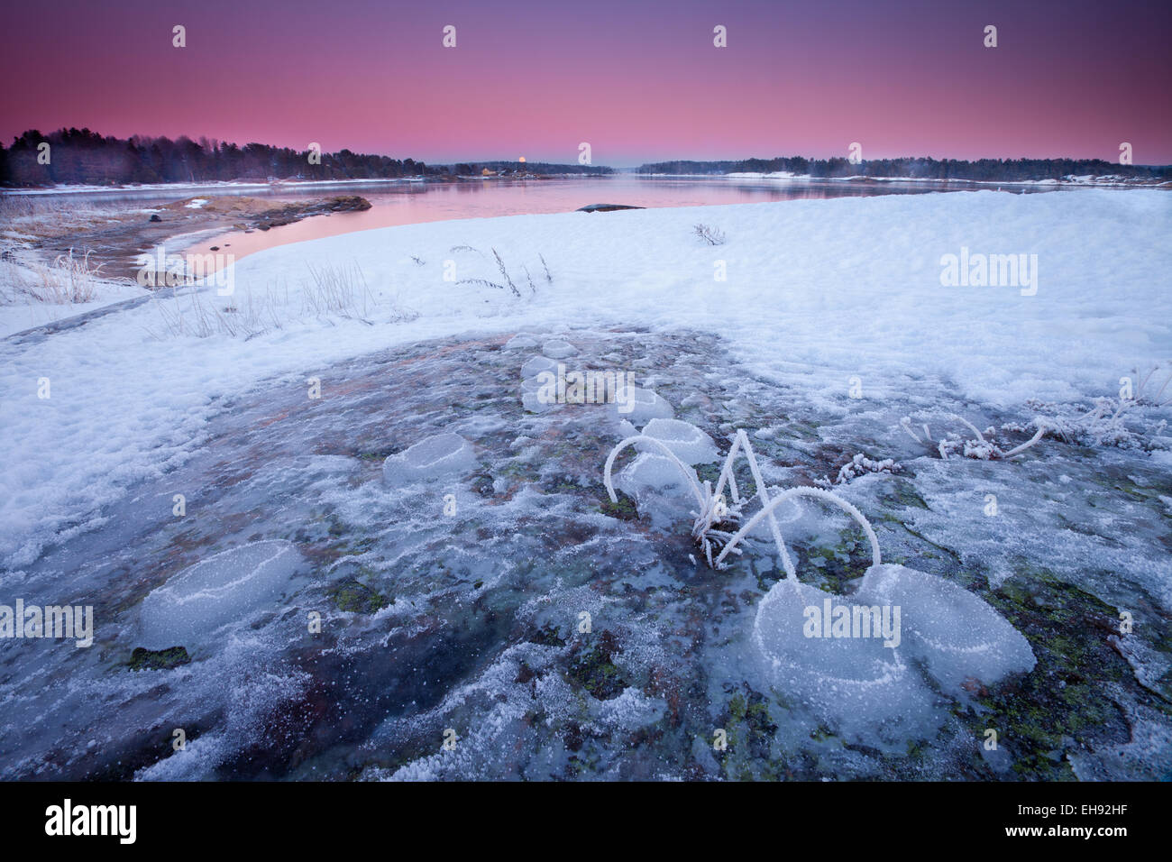 Colorful winter evening skies and moonrise by the Oslofjord, at Oven in Råde kommune, Østfold fylke, Norway. Stock Photo