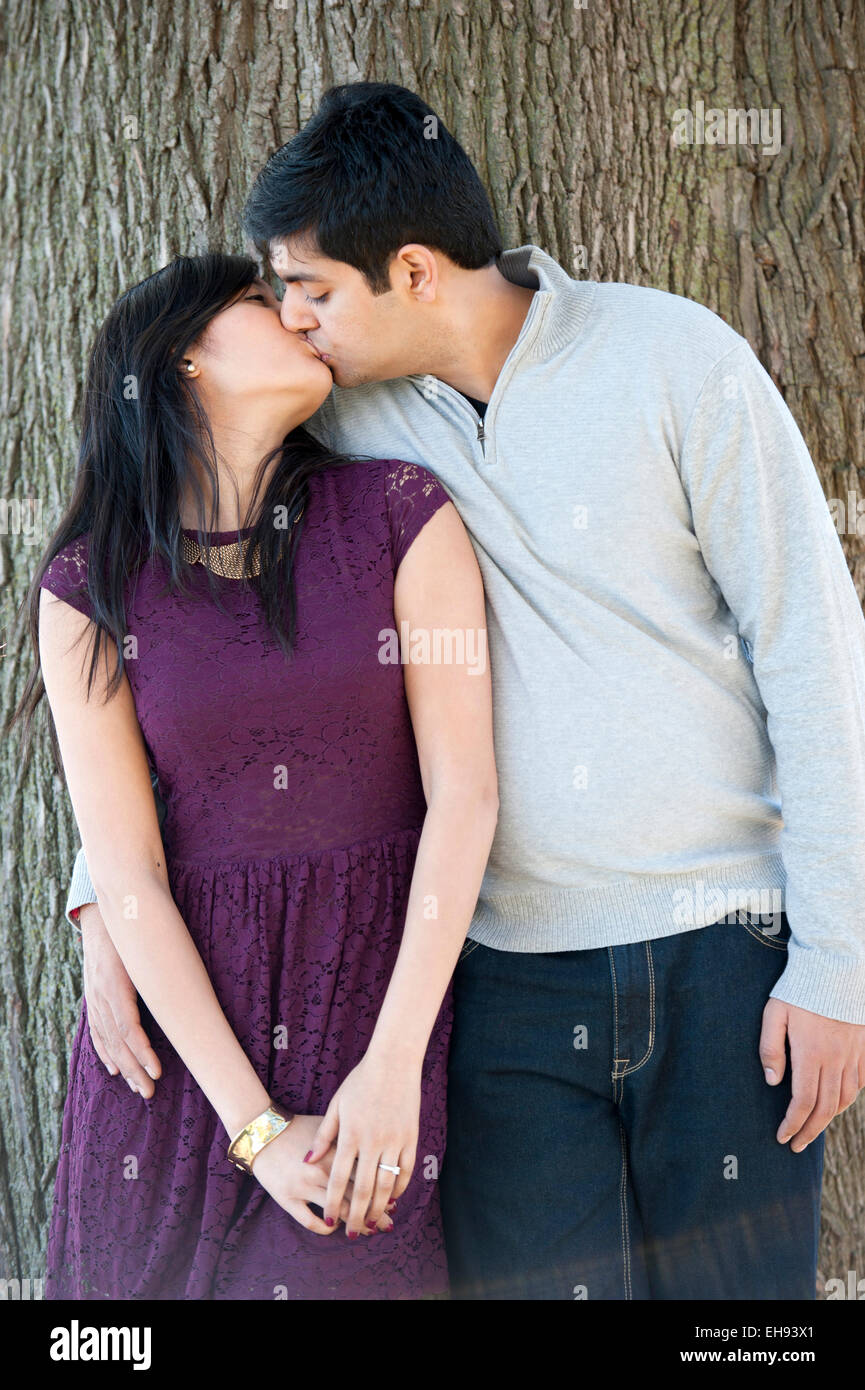 A young and happy Indian couple kissing with a tree background on a cloudy  day Stock Photo - Alamy