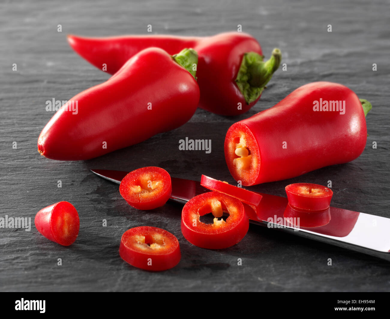 Fresh red chillies whole & cut on a black background,  composed arrangement Stock Photo