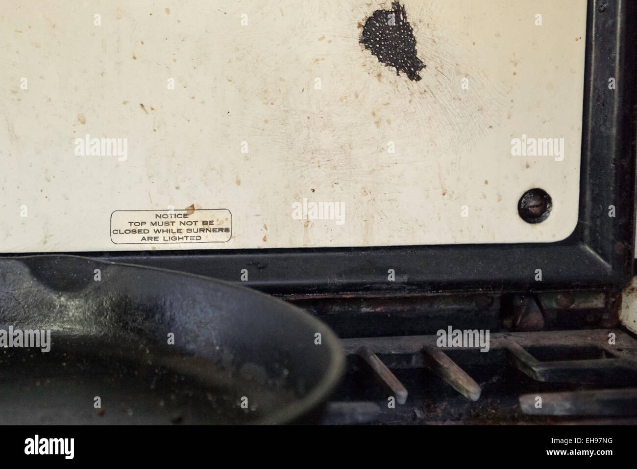 well used and dirty cast iron pan on antique stove, chip in enamel