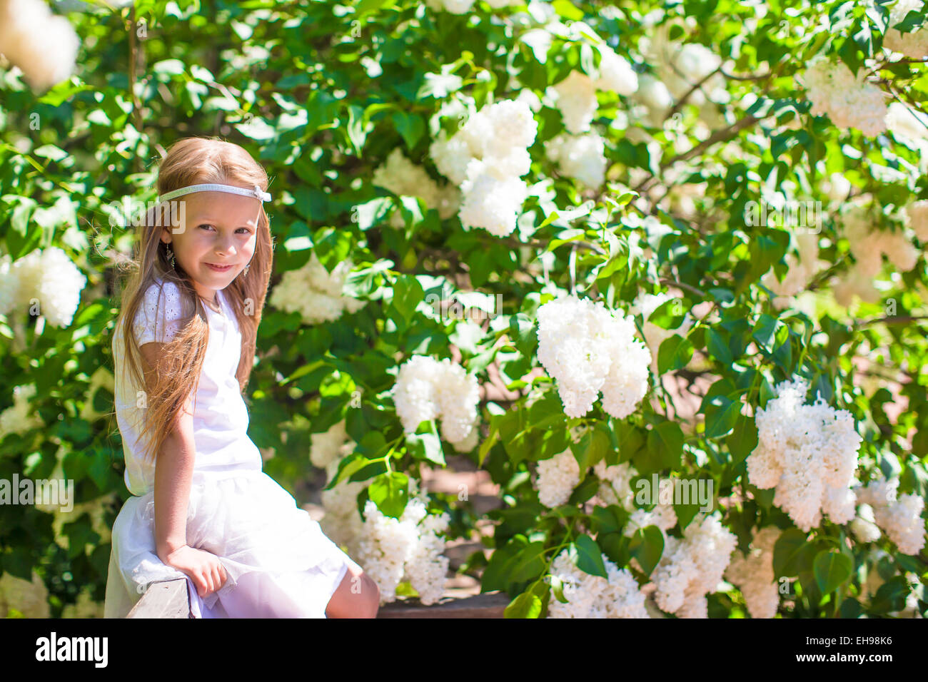 Adorable happy little girl in flower blossoming garden Stock Photo - Alamy