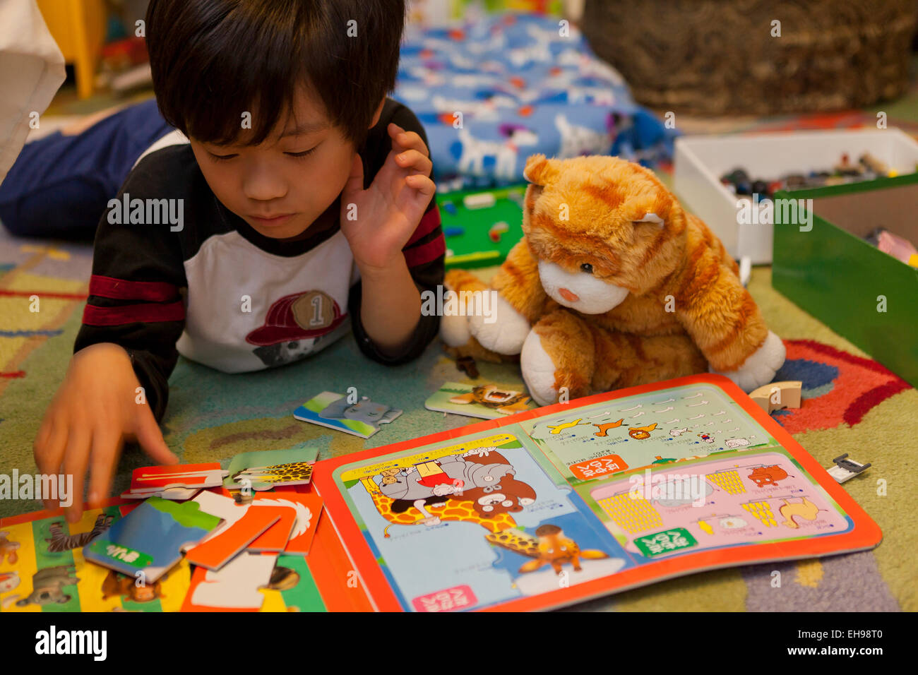 Child playing board game with stuffed cat Stock Photo