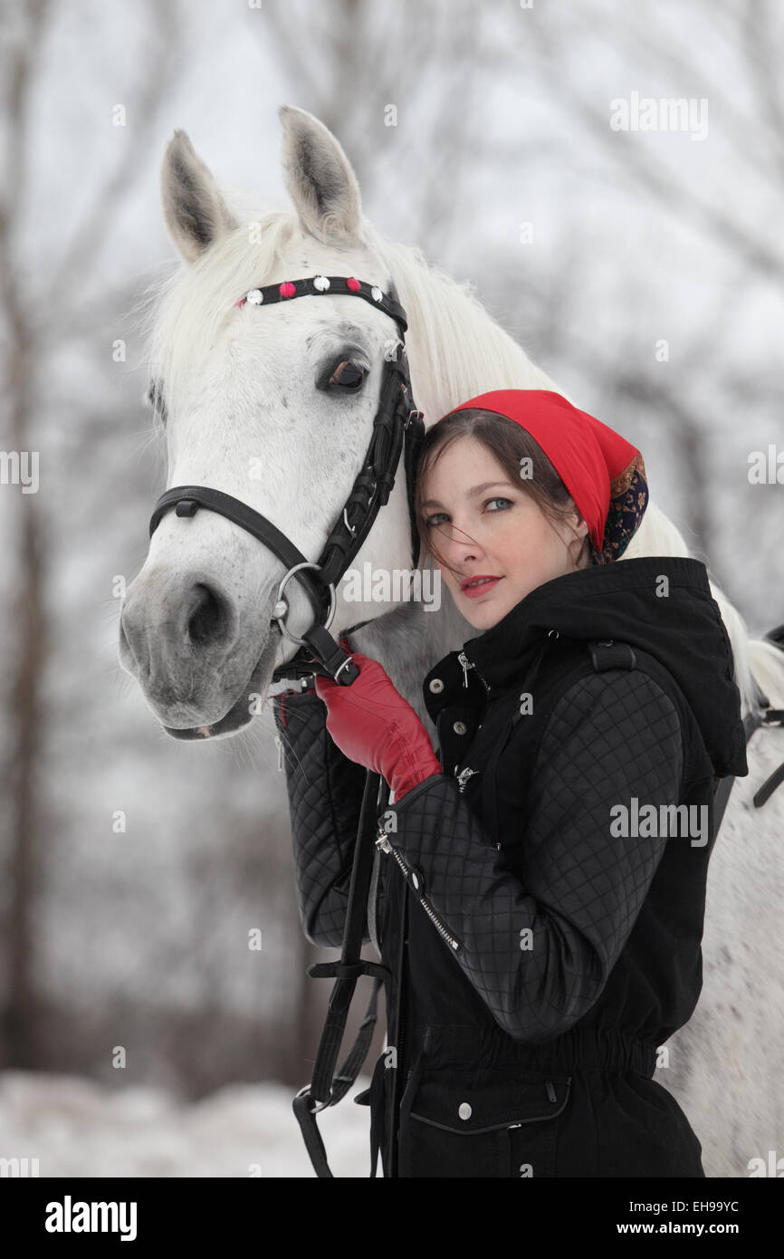 Horse and pretty brunette woman in winter countryside Stock Photo