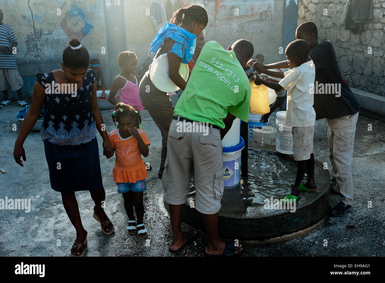 Haitians fill plastic barrels with safe drinking water from a public water pump in Portau