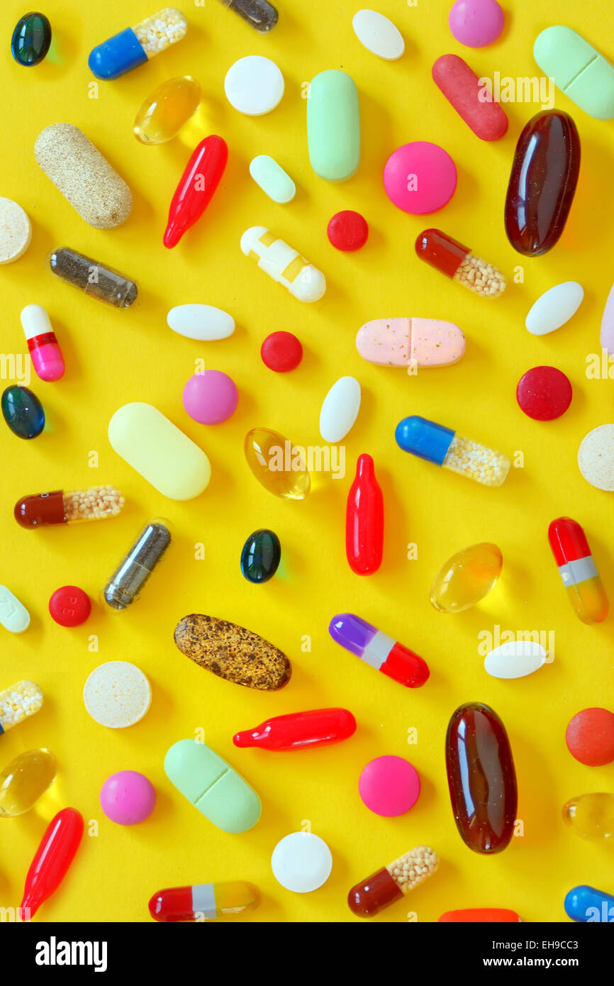 Many colorful pills on yellow background Stock Photo