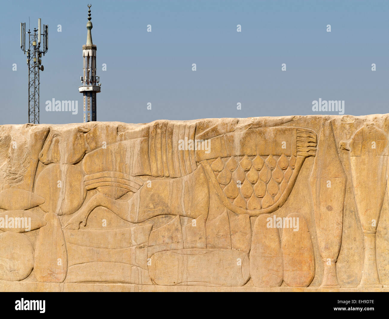 view of relief block showing offerings in front of pylon and minaret  in Luxor, taken within Karnak Temple. Egypt Stock Photo