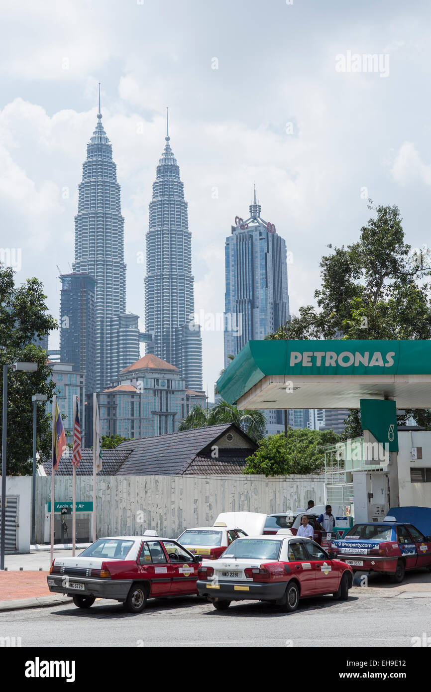 Taxis line up to fill up at a Pertoliam Nasional Bhd. (Petronas) gas station stands with the Petronas Twin Towers in the background, in Kuala Lumpur, Malaysia Stock Photo