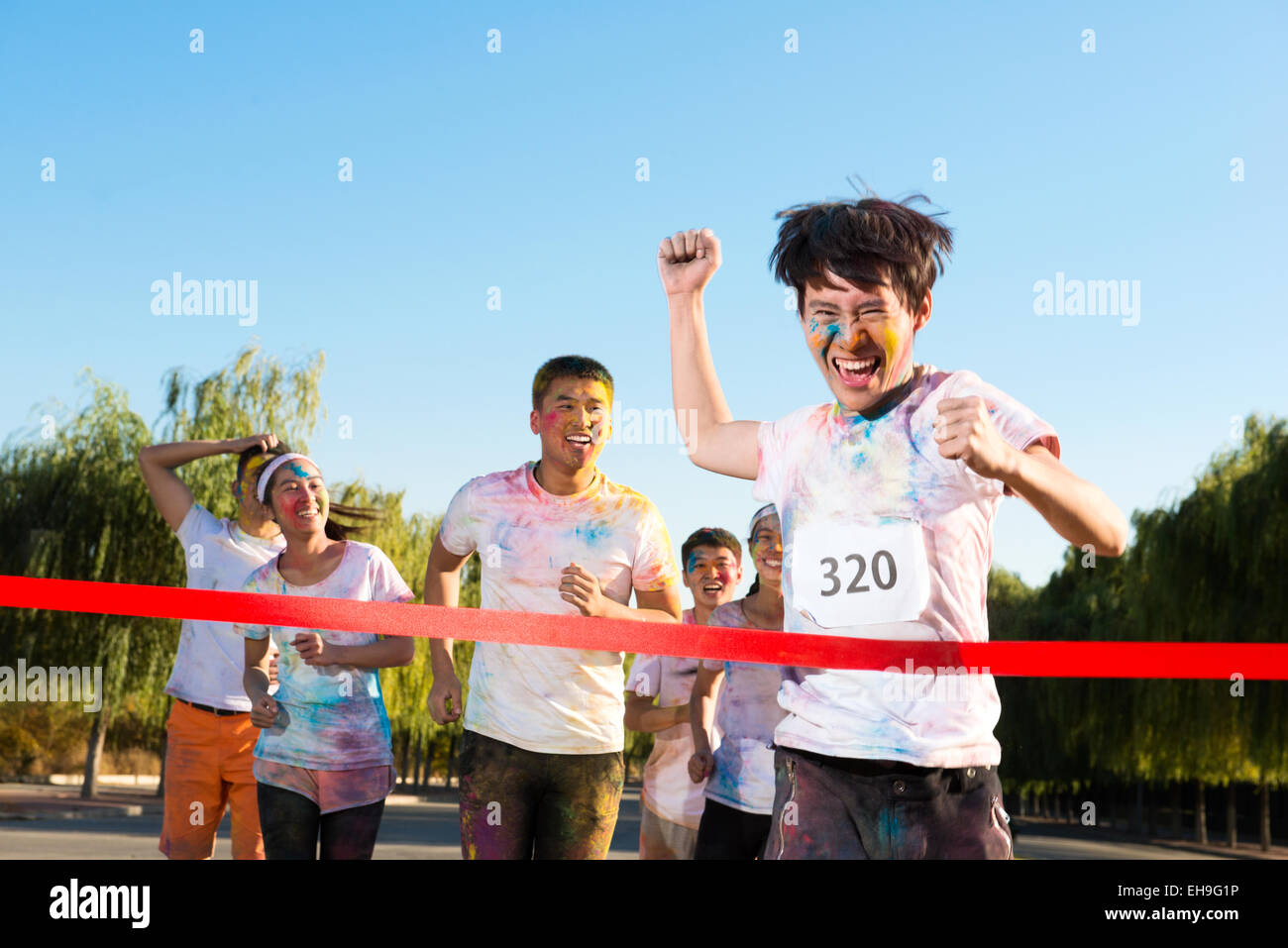 Young man crossing finishing line at The Color Run Stock Photo