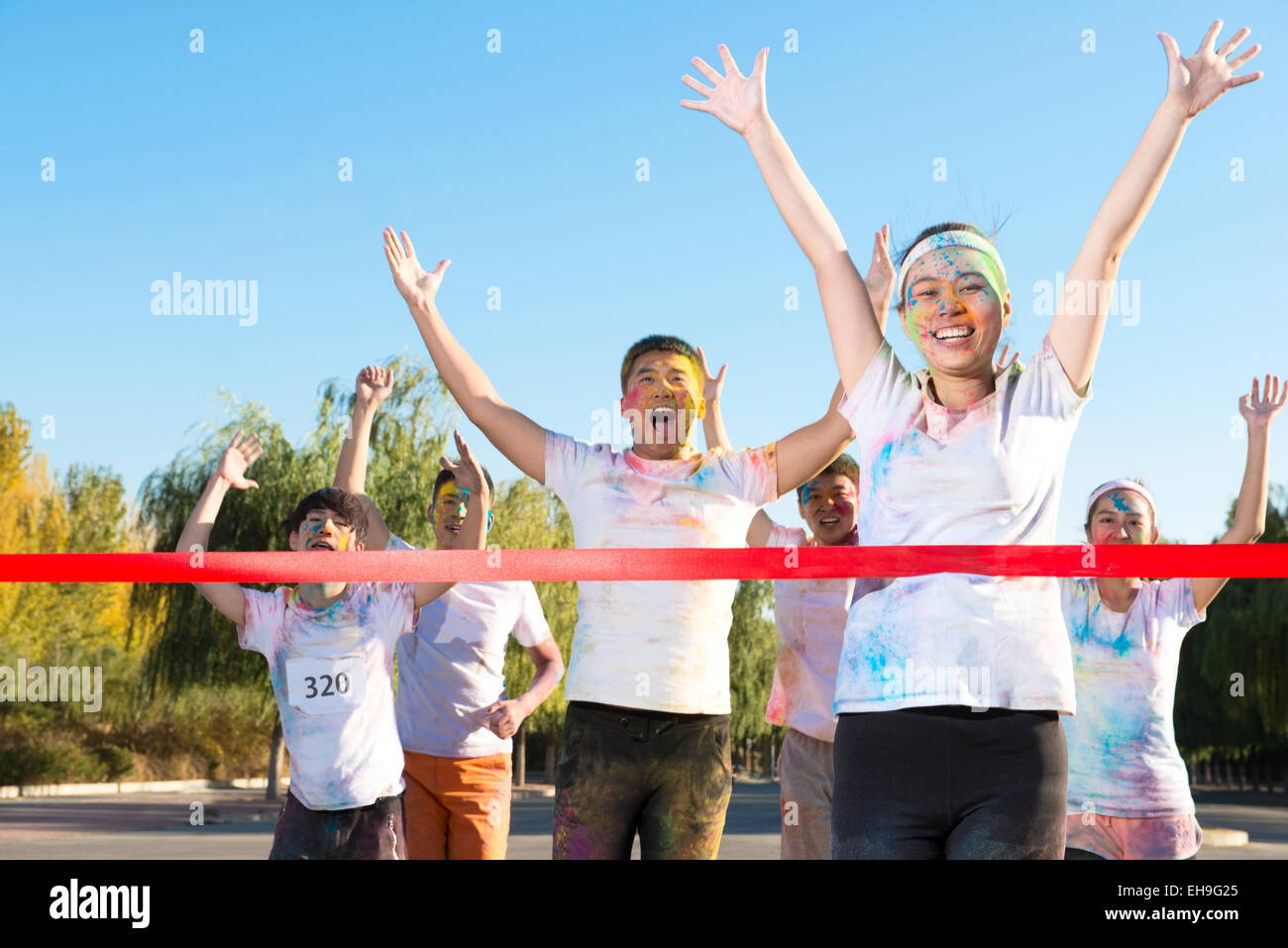 Young woman crossing finishing line The Color Run Stock Photo