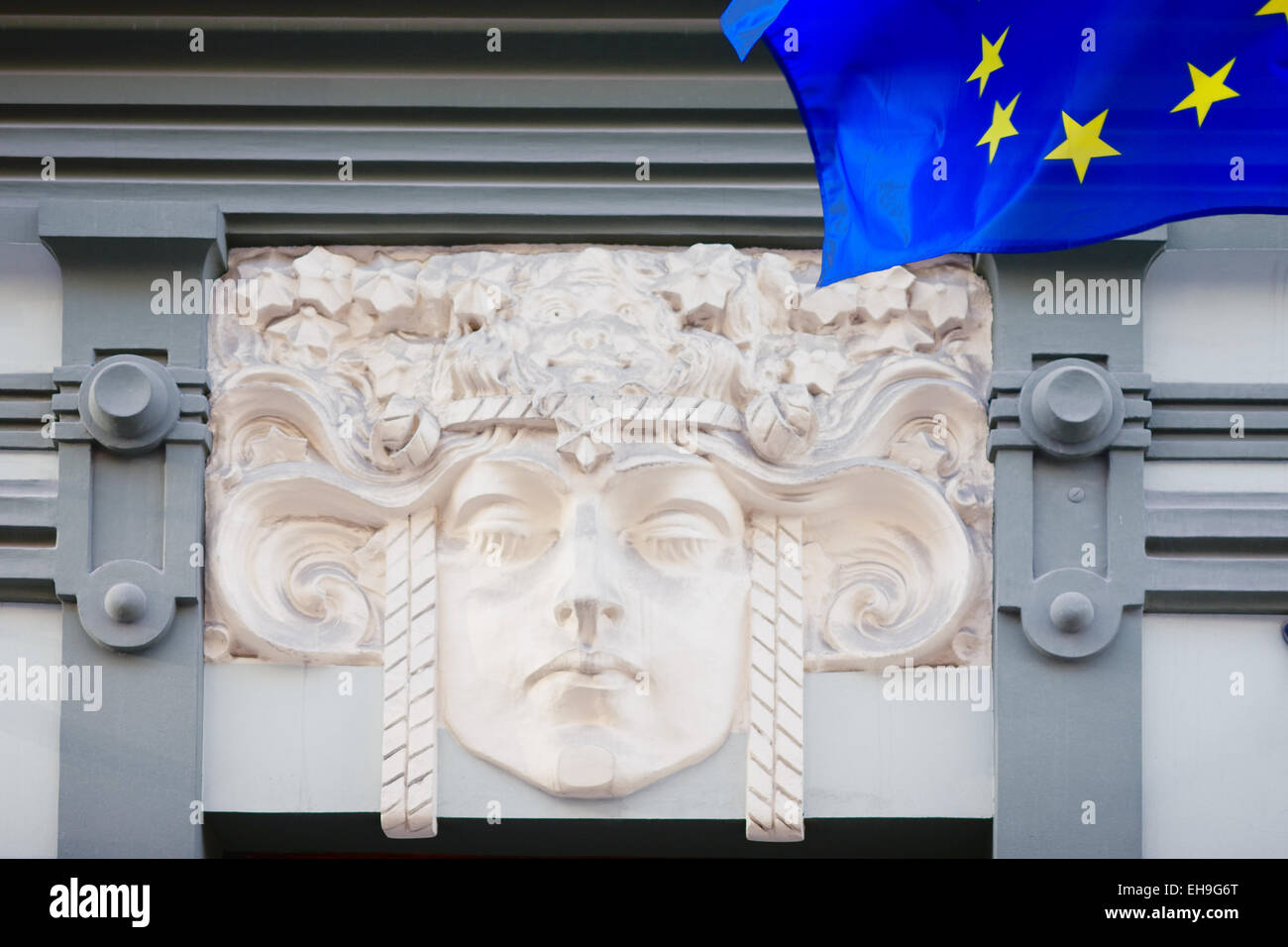 Bas-relief of a woman's head on the wall of an old house and the EU flag in the Old Town. Vecriga, Latvia Stock Photo