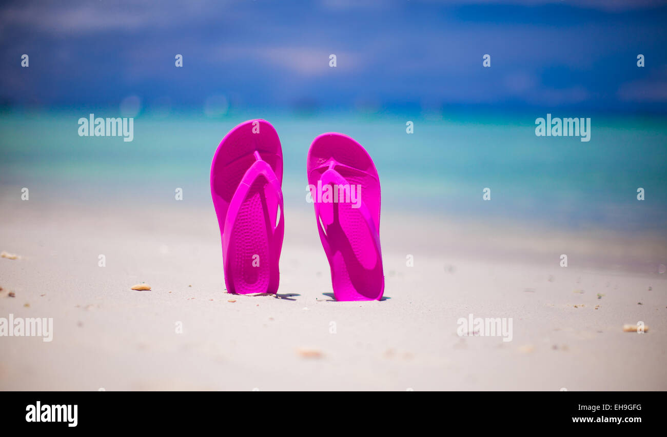 Pink vibrant beach flip flops on white sand on sea background Stock ...