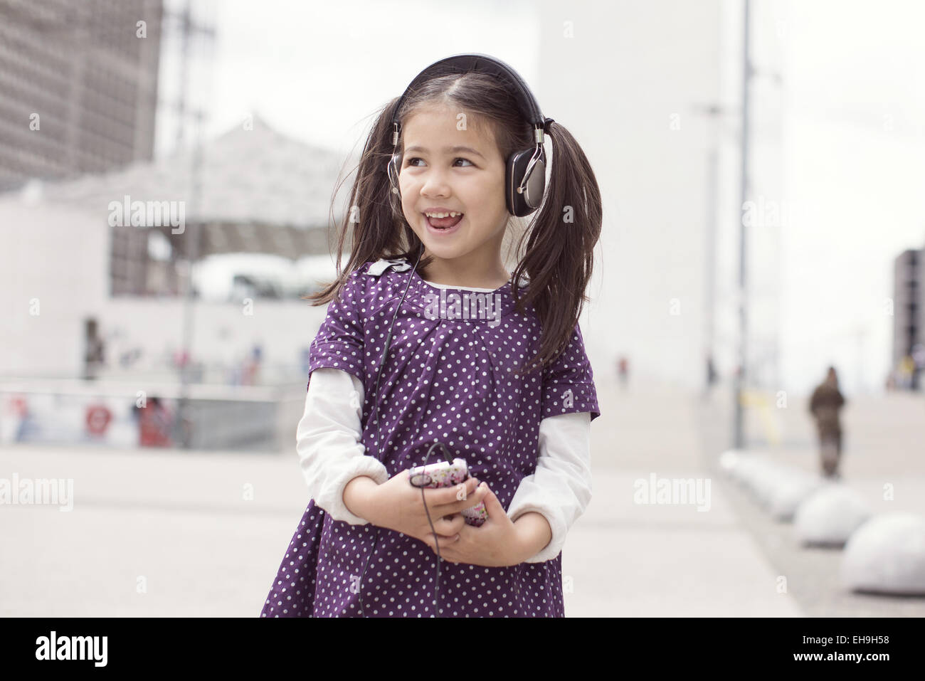 Girl listening to headphones and singing outdoors Stock Photo