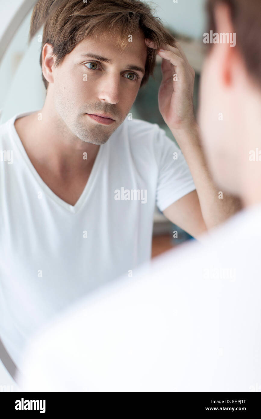 Man with receding hairline looking at self in mirror Stock Photo