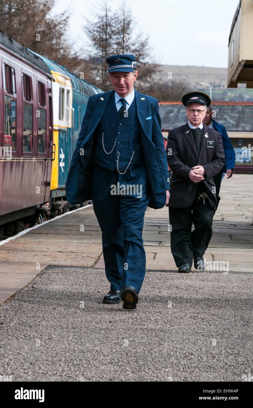 A train guard in a 1970s and 1980s period British Rail Guards uniform walking along the platform at Rawtenstall on the East Lanc Stock Photo