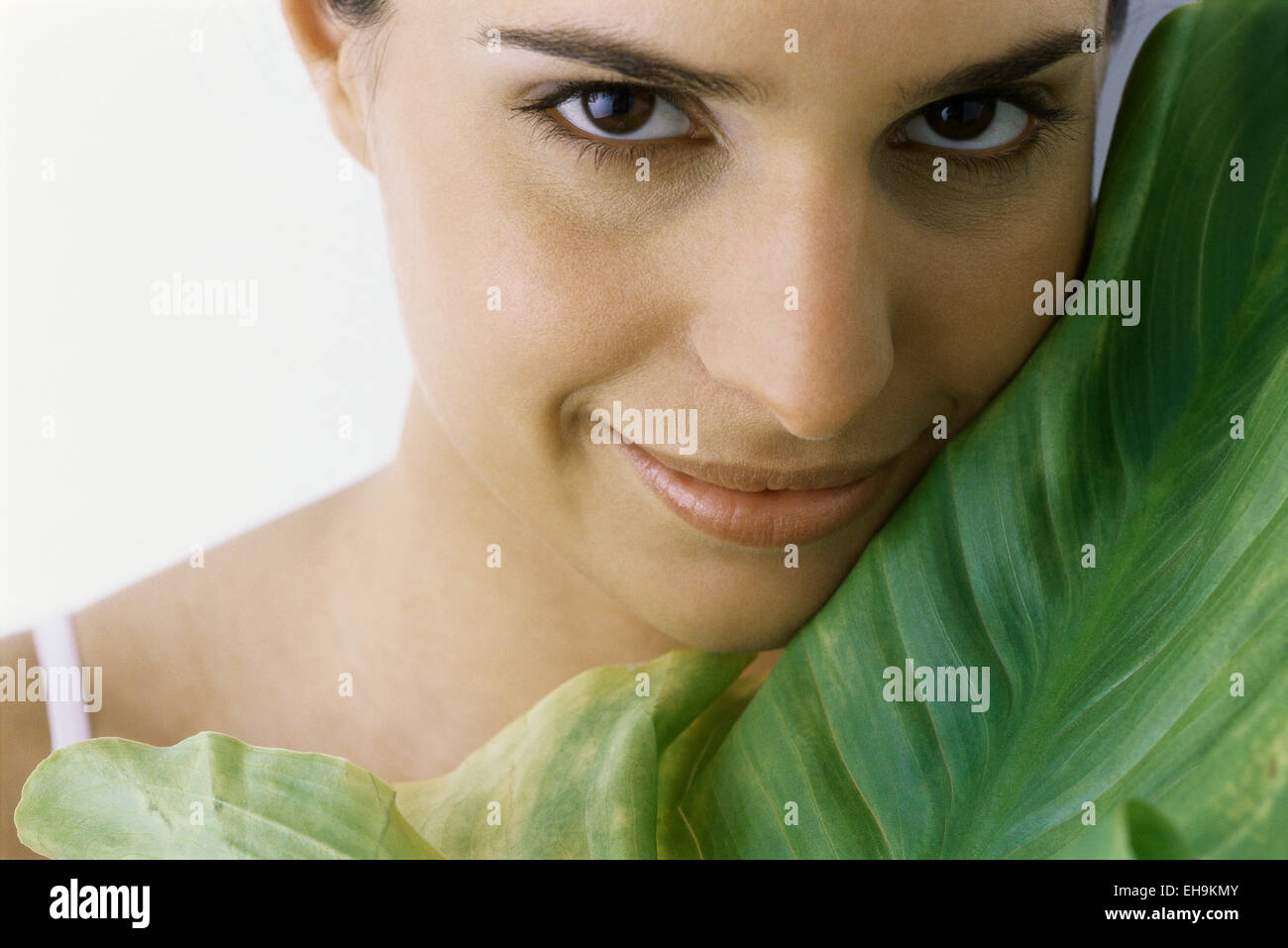 Young woman holding large leaf against cheek, portrait Stock Photo - Alamy