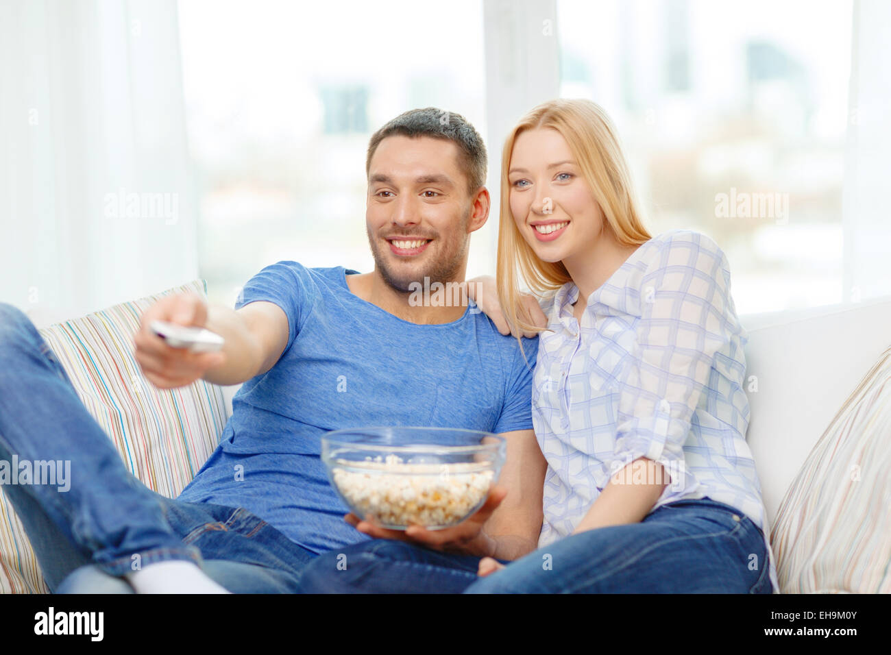 smiling couple with popcorn watching movie at home Stock Photo