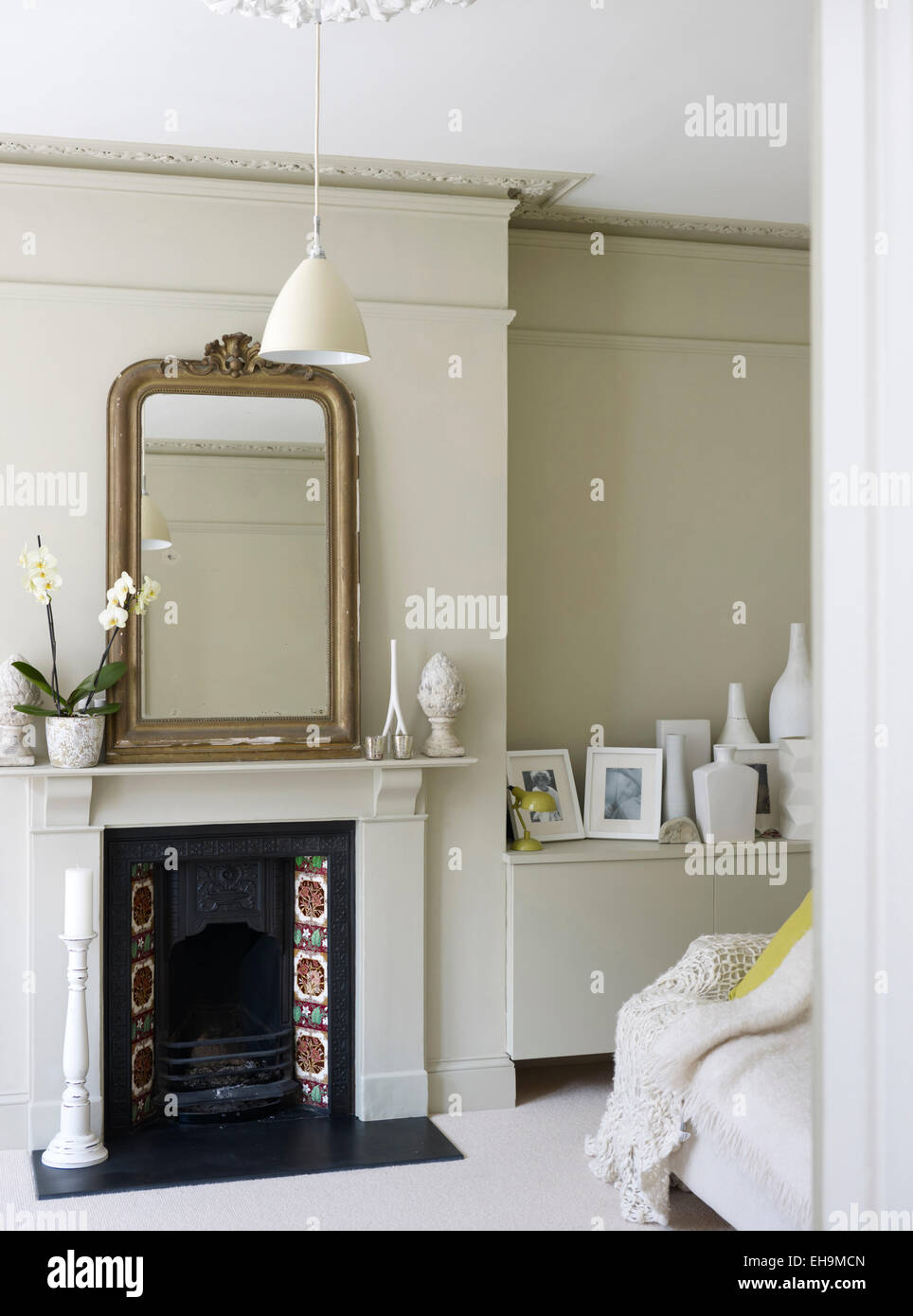 Mirror on mantlepiece above tiled fireplace in white sitting room ...
