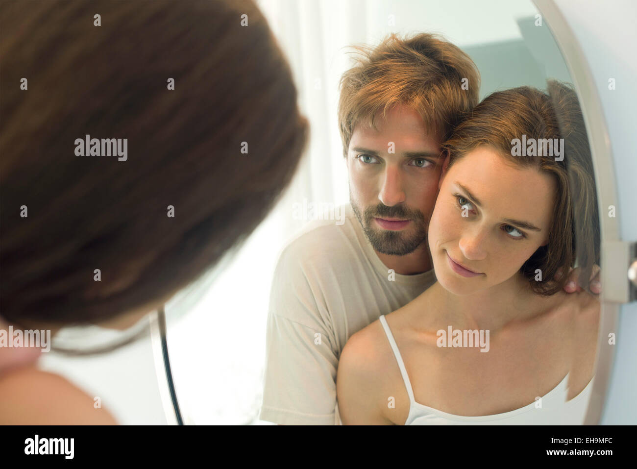 Couple cheek to cheek, looking at each other in mirror Stock Photo