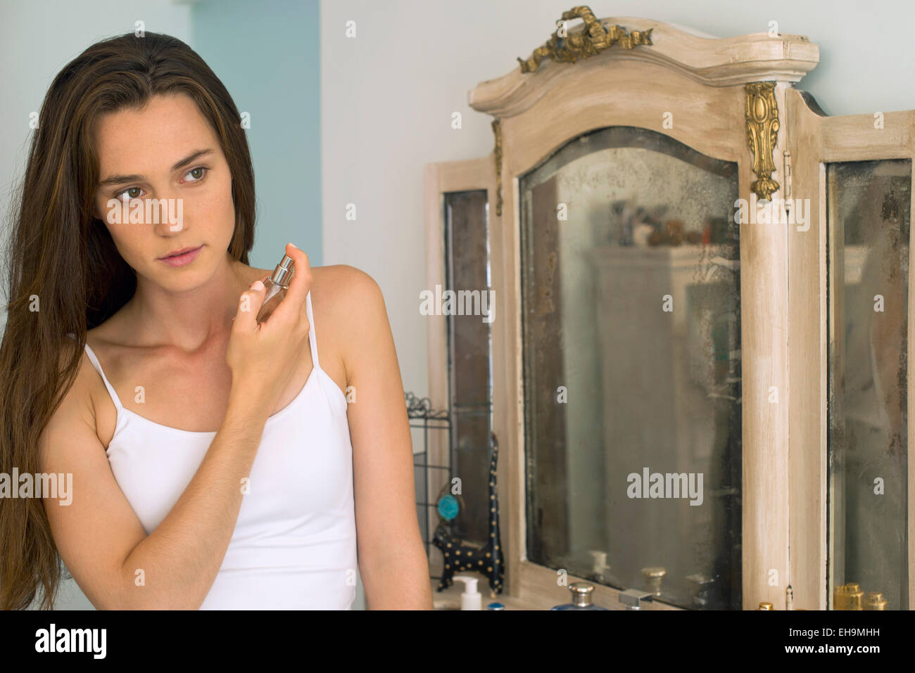 Woman putting on perfume Stock Photo