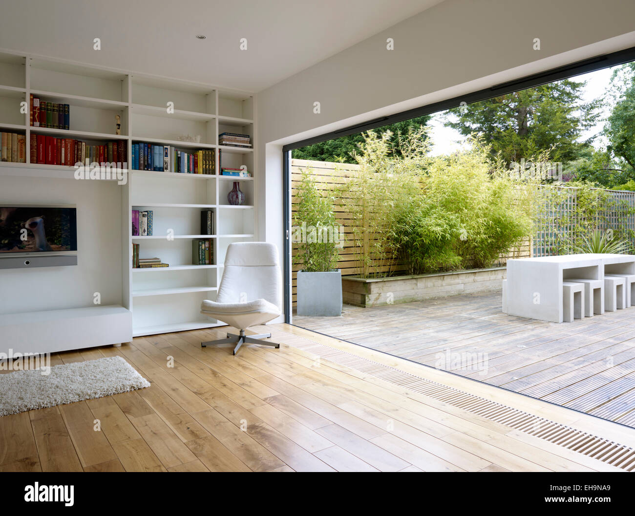 Full wall shelf with TV in wooden floored living room with open wall to courtyard at Radinden