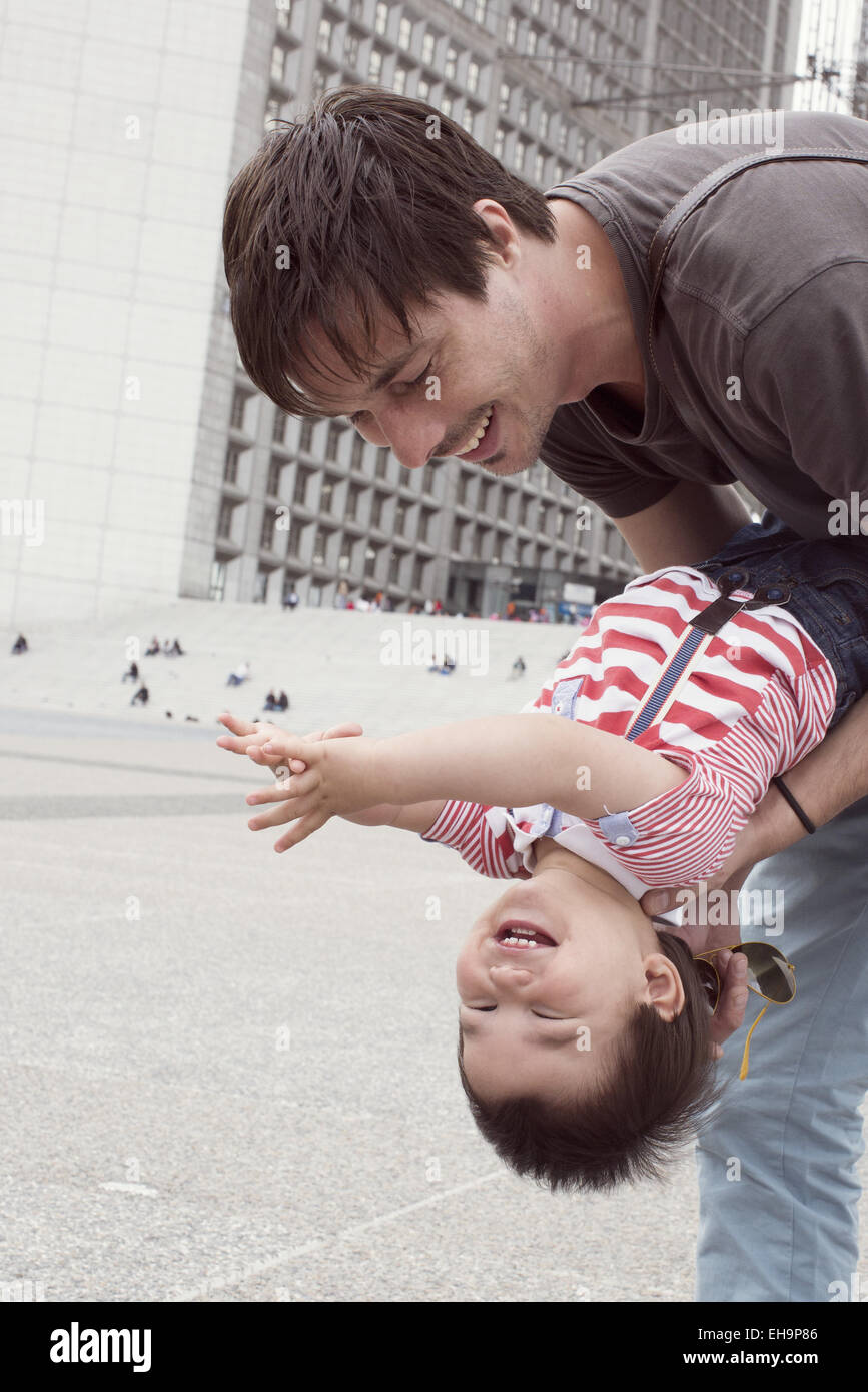 Father holding young son upside down, both laughing Stock Photo