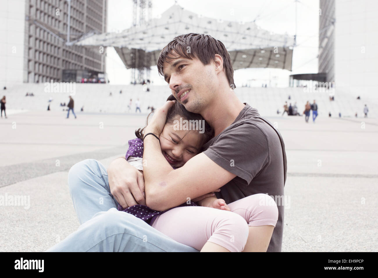 Father holding young daughter in his lap outdoors Stock Photo