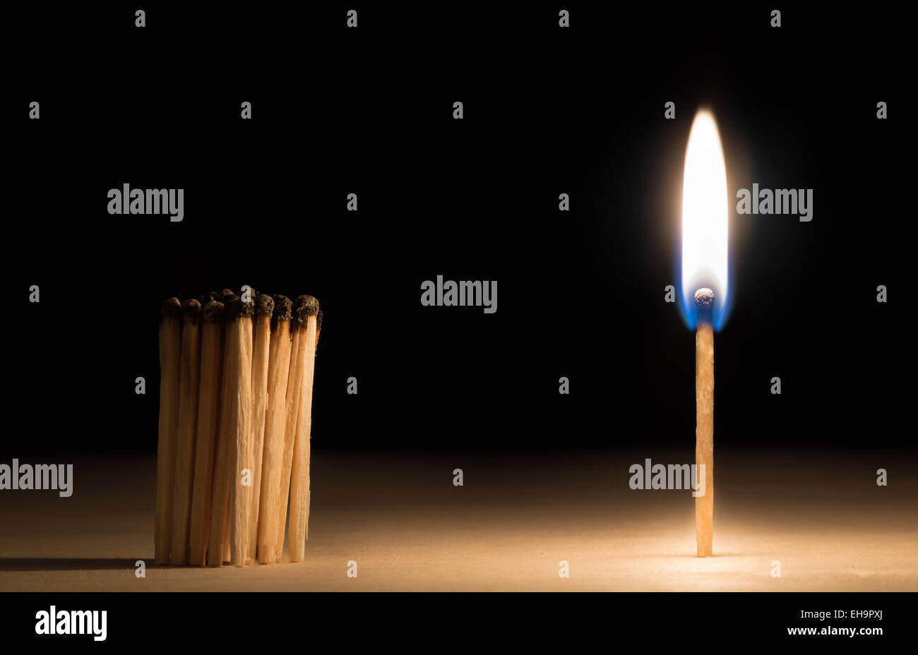 Crowd of burnt  matches standing before match on fire concept of motivation leadership on black Stock Photo