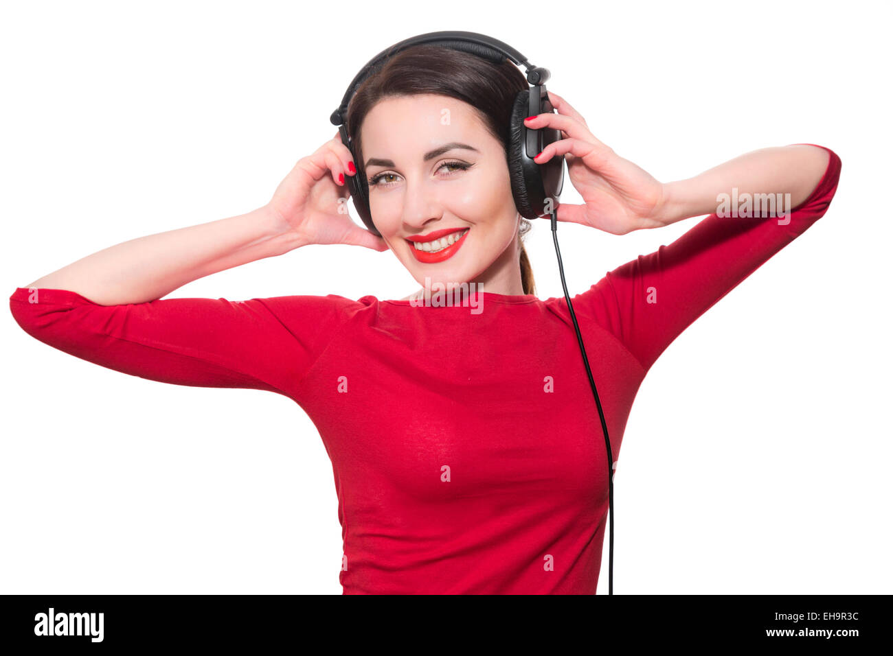 Wonderful teenager girl  listening to the music in big headphones in red clothes islolated on white background Stock Photo