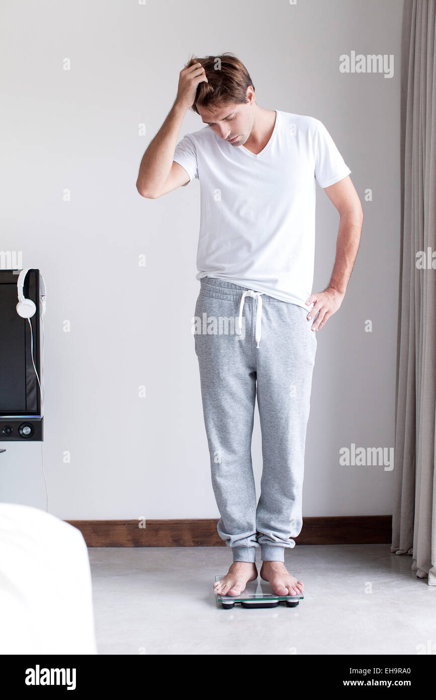 Man weighing self on bathroom scale Stock Photo