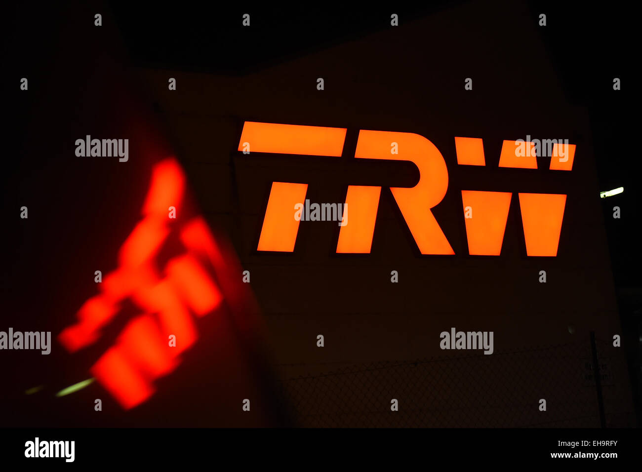 The logo of American car parts maker TRW Automotive is illuminated at a factory building and is reflected in a car window in Radolfzell, Germany, 09 March 2015. The German car parts maker ZF Friedrichshafen AG is about to conclude a deal worth billions of euros: ZF will acquire TRW Automotive. With the acquisition, ZF will move up into the ranks of the biggest automotive suppliers worldwide. PHOTO: FELIX KAESTLE/dpa Stock Photo