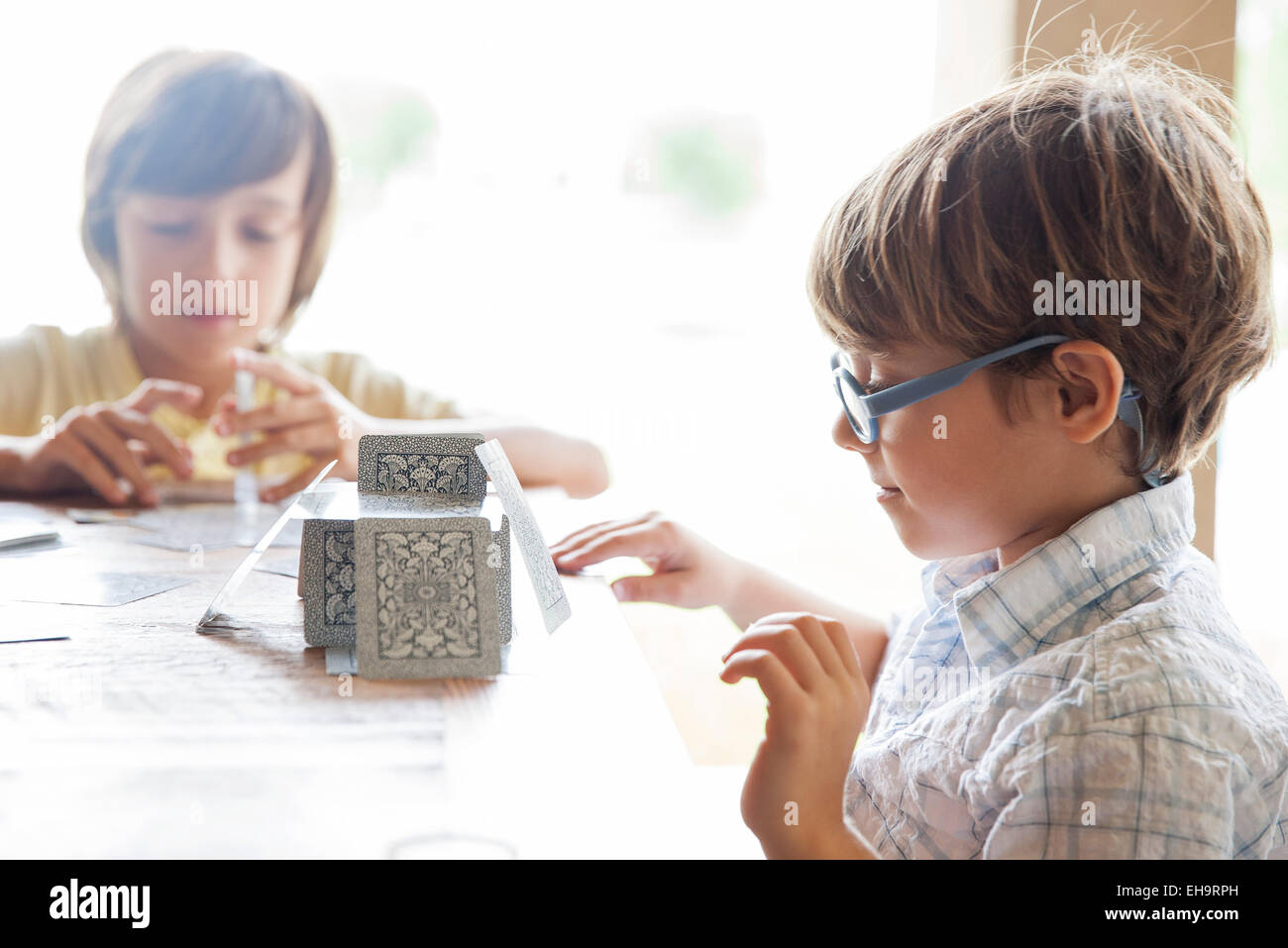 Boys building house of cards together Stock Photo