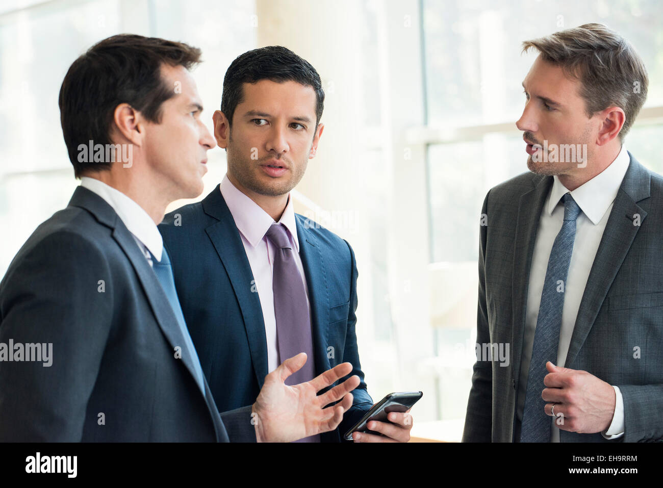 Businessmen standing together having serious discussion Stock Photo Alamy