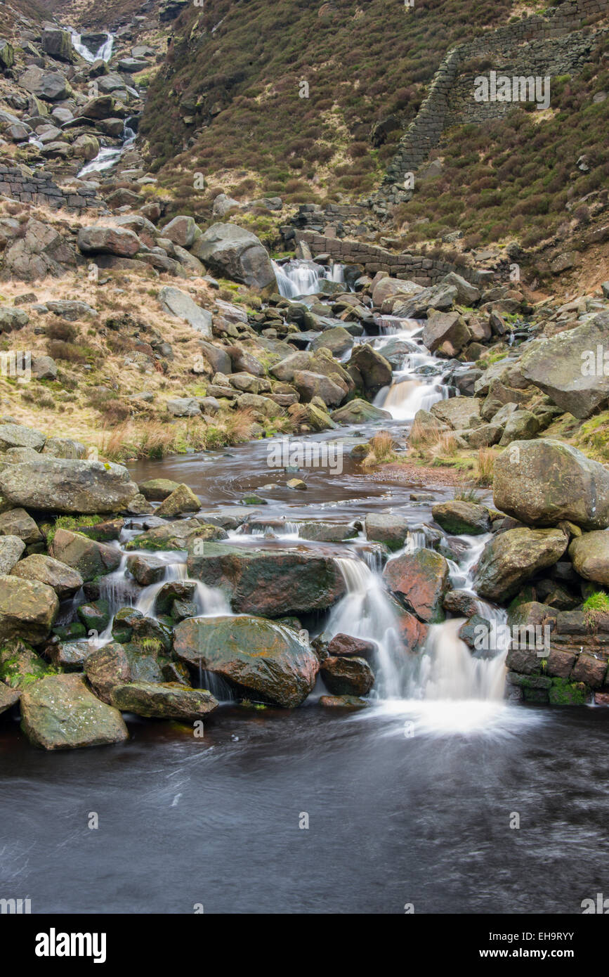 A small stream tumbling over fallen millstone grit blocks in a valley in the Northern Peak District area of Saddleworth close to Stock Photo